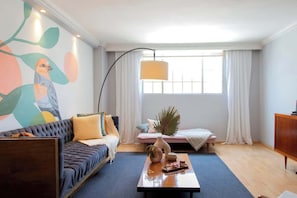 Uma sala de estar moderna com um sofá, uma mesa de centro e uma janela grande com cortinas.