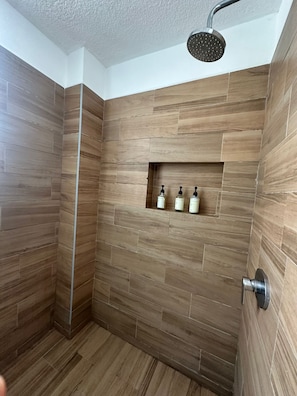 A shower with wooden walls and a shelf with toiletries.