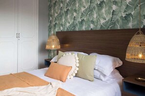 A neatly made bed with a white and orange blanket, surrounded by pillows in various colors and textures. - NEW Space & style in coveted Polanco, walk to all! (Ciudad de México)