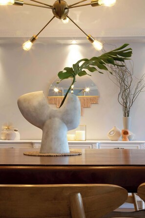 Um interior moderno com um vaso escultórico único como peça central, uma área de refeições minimalista e uma luminária contemporânea.