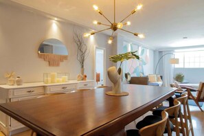 A modern dining area with a wooden table, chairs, a chandelier, and decorative items.