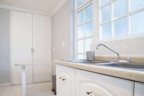 A kitchen with a white countertop, a sink with a modern faucet, and a window above the sink.