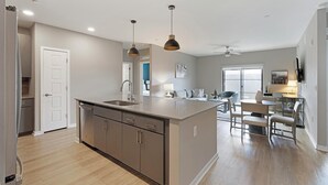 Eine moderne Küche mit einer zentralen Kochinsel, einem Essbereich mit Tisch und Stühlen sowie einem Deckenventilator.