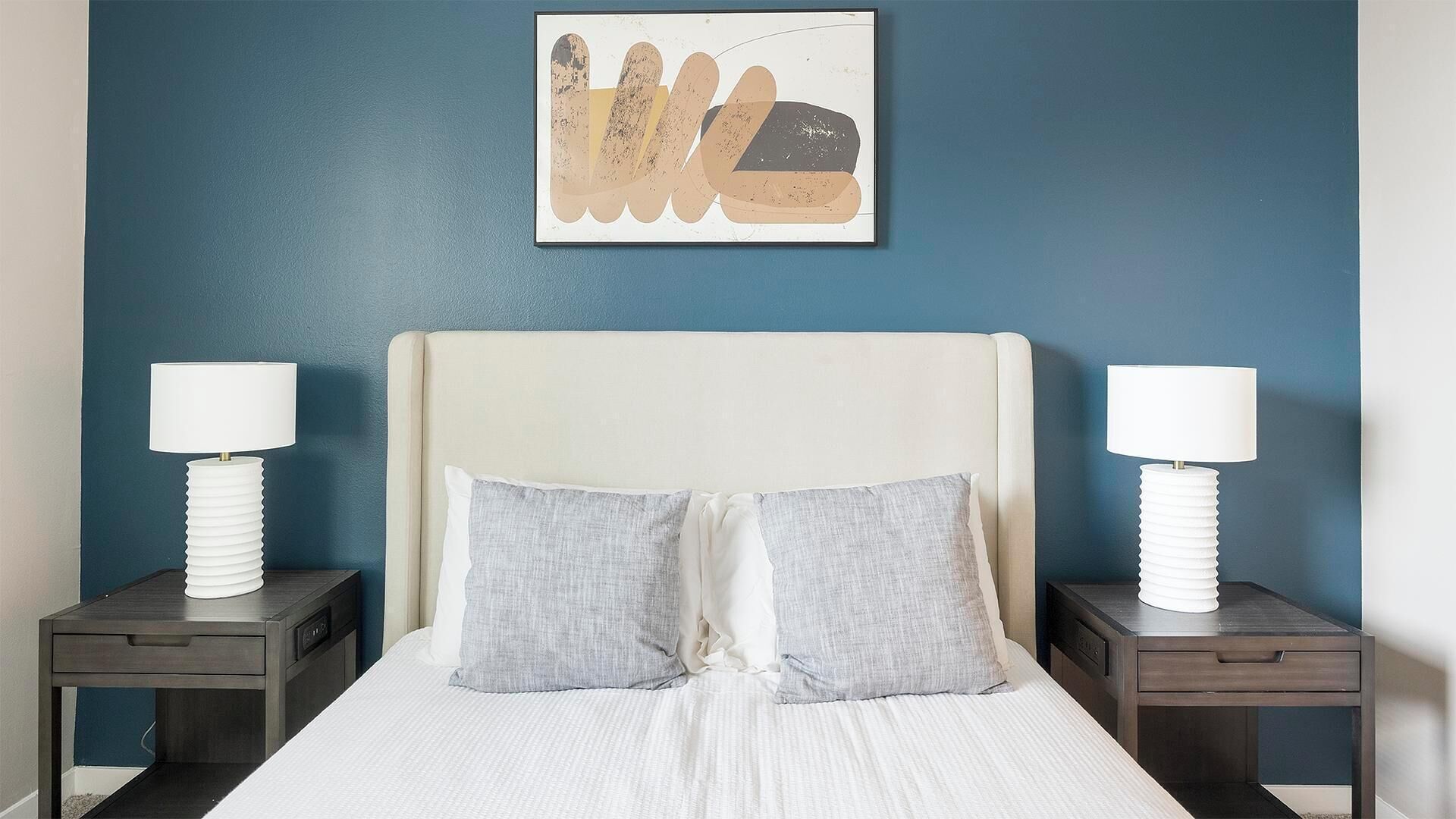 Een netjes ingerichte hotelkamer met een groot bed, twee nachtkastjes met lampen en een aan de muur hangend kunstwerk.
