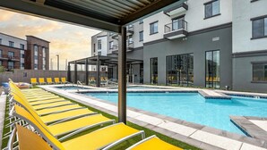 Ein modernes Gebäude mit Schwimmbad, gelben Liegestühlen und einem überdachten Sitzbereich.
