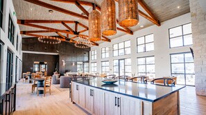 A spacious kitchen with a large island, wooden beams, and large windows. - Landing | Chic 2BD, Pool, Yoga Studio (Fort Worth)