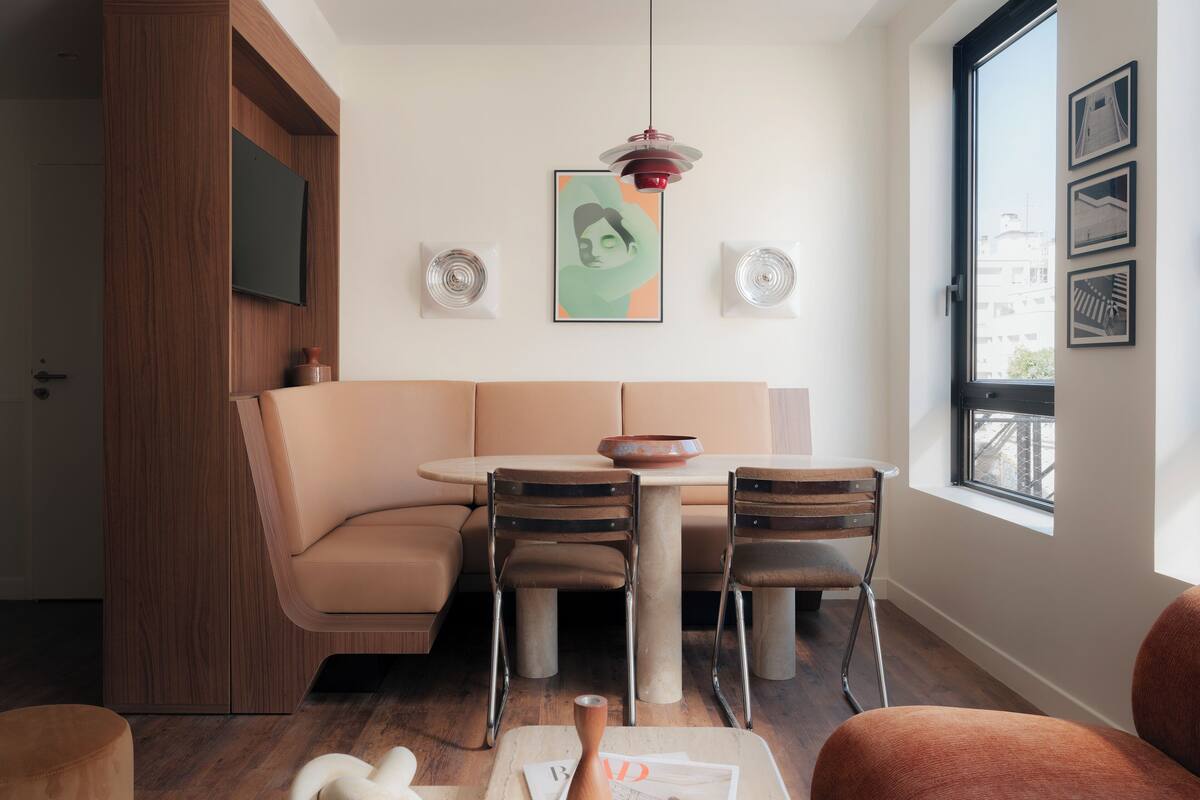 Een moderne woonkamer met een beige bank, een ronde tafel en een groot raam.