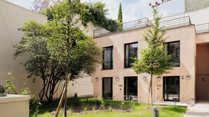 A modern building with numbered doors, a grassy courtyard, and trees.