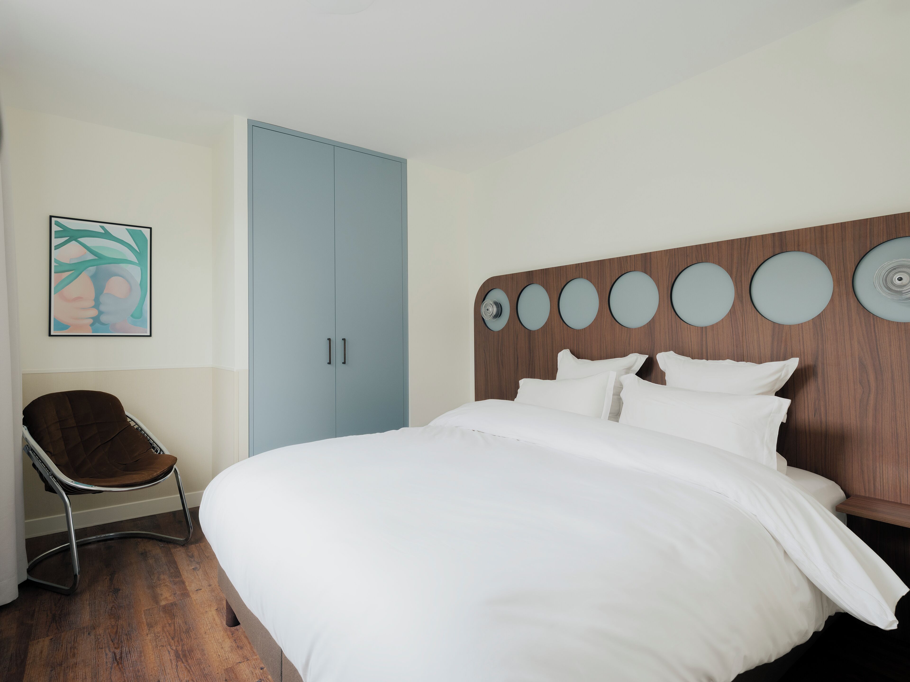 Ein Schlafzimmer mit einem Bett, einem Sessel, einem Kleiderschrank und einer Wand mit runden Spiegeln.