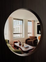 A circular window view of a modern living room with a sofa, a coffee table, and a chair.
