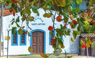 Un edificio con un letrero que dice 'Capela Santo Antonio' y una puerta de madera grande.