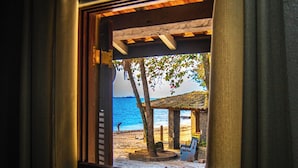 A window with a view of a beach, a wooden structure, and a bench.