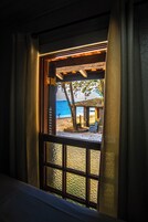 Una ventana con vista a la playa, una estructura de madera y un banco.