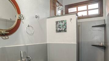 A bathroom with two sinks, a toilet, a shower, and a window.