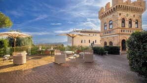 A courtyard with outdoor seating, a large brick building, and a clear sky.