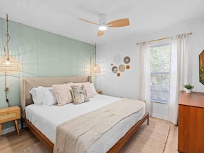 A bedroom with a bed, a ceiling fan, a window with curtains, and wall decor. - Super Boho - At Lake Toho's Water (Kissimmee)