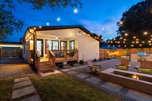 Una cabaña acogedora con un porche cubierto, mobiliario exterior y una chimenea.