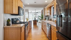 Una cocina moderna con armarios de madera, electrodomésticos de acero inoxidable y una isla central.
