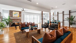 Amplia sala de estar con pared de ladrillo, muebles de madera y ventanas grandes.