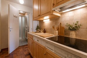 A modern kitchen with wooden cabinets, a black stovetop, and a tiled backsplash.