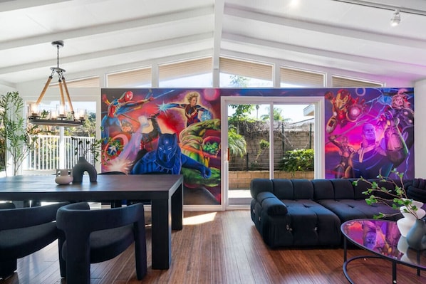 Un espacio habitable amplio con un mural grande, una mesa de comedor y un sofá.