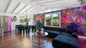 A modern living room with a black sofa, a round coffee table, and a vibrant mural on the wall.