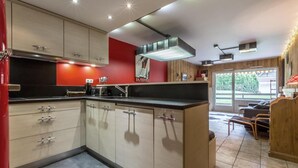 A modern kitchen with light wood cabinets, a black countertop, and a red accent wall.