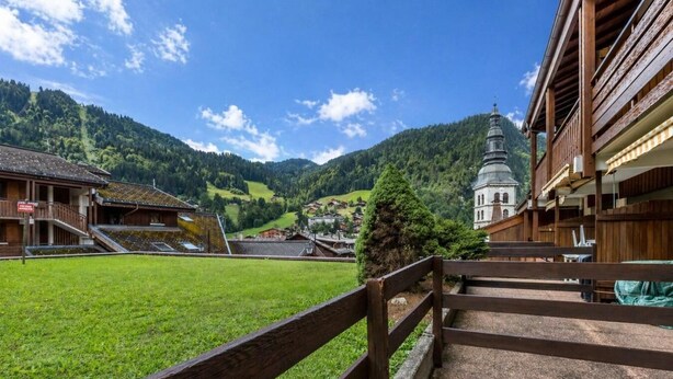 A rural village with a church, wooden buildings, and a grassy field.