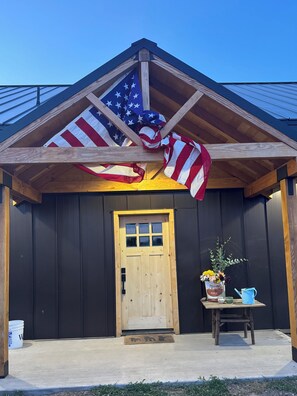 A wooden building with a dark facade, a wooden door, and a small porch area with a table and a potted plant. - Quiet, peaceful, get out of the hustle game and appreciate logging history. (Bly)