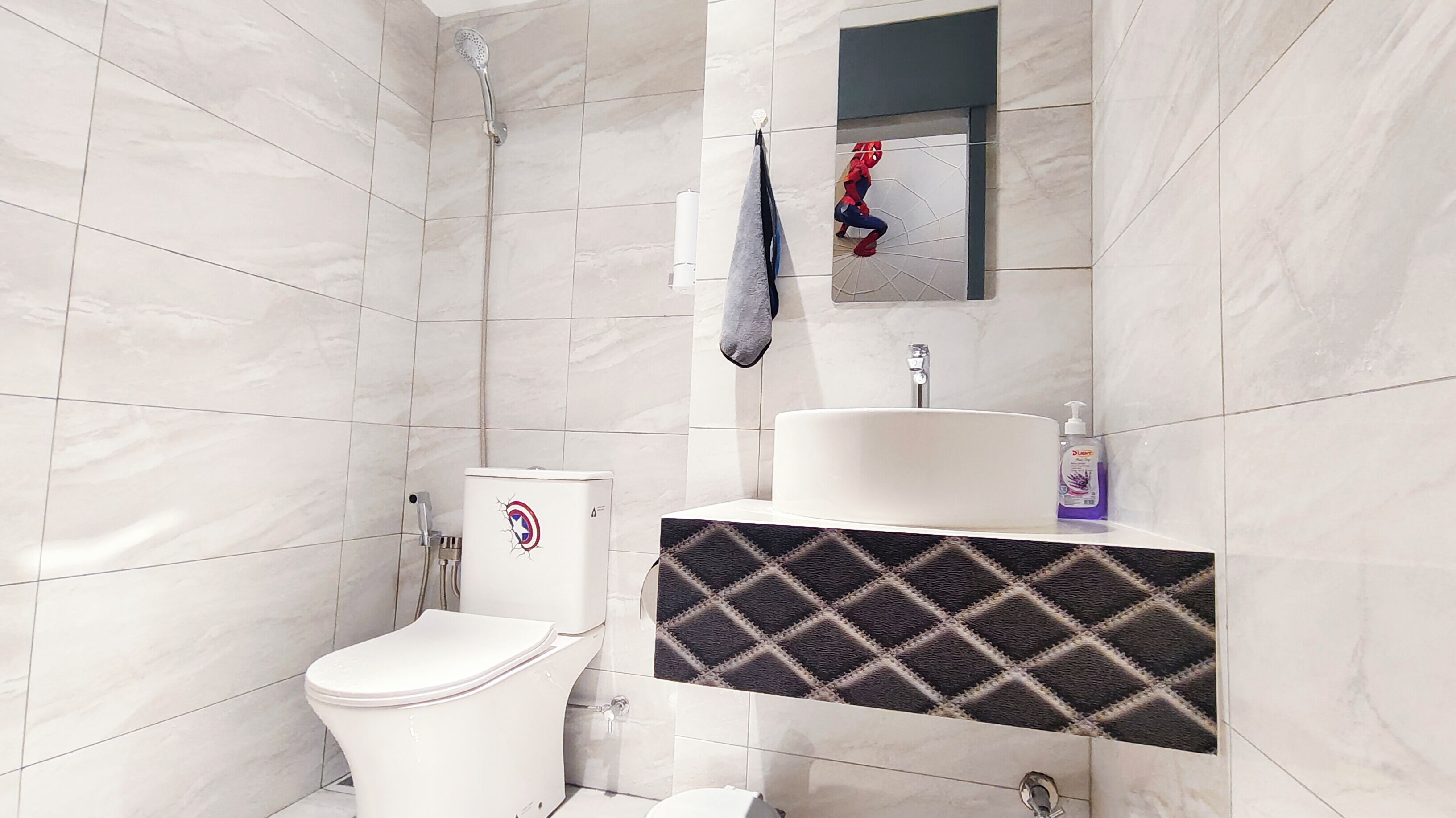 A modern bathroom with a white toilet, a shower, and a sink with a marble countertop.