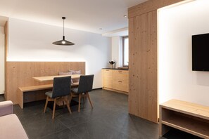 A modern kitchen with wooden cabinetry, a dining table with chairs, and a pendant light.