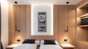 Een moderne slaapkamer met een wandpaneel van hout, een centraal lichtarmatuur en drie ingelijste foto's aan de muur.
