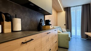 Une cuisine moderne avec des meubles en bois, un four encastré et un coin repas comprenant un canapé et des rideaux.