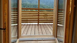 A wooden balcony with a view of a forested mountain range. - Attico Stella Alpina (Andalo)