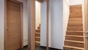 A modern interior with a wooden staircase, a large mirror, and a door. - Attico Stella Alpina (Andalo)