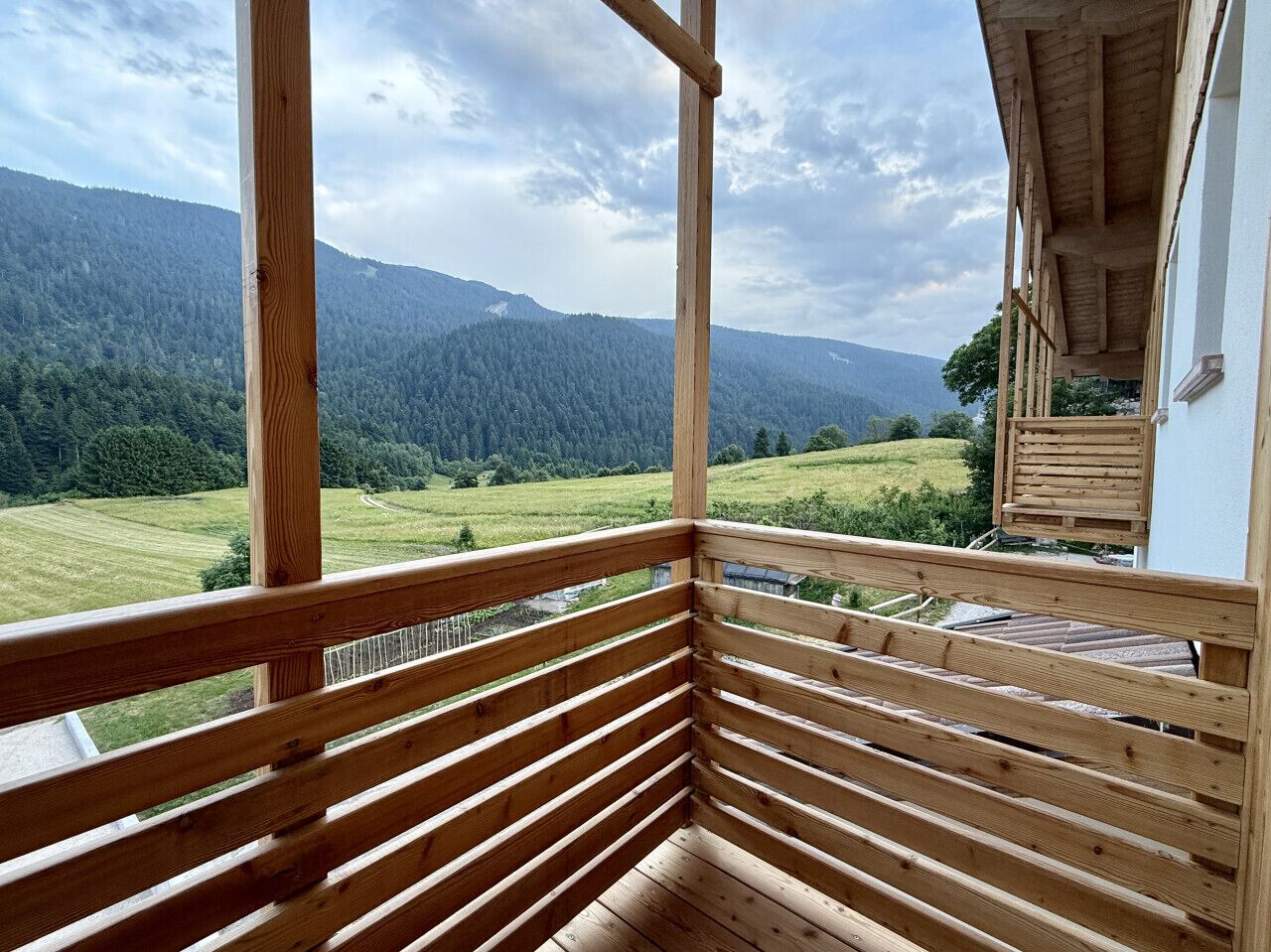A wooden balcony with a view of a mountainous landscape.