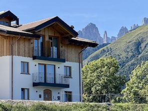 Un bâtiment en bois à deux étages, doté de balcons, qui se dresse sur un fond de paysage montagneux.