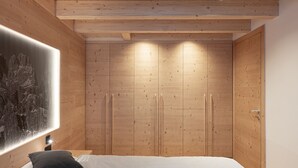 A bedroom with a bed, a wall-mounted light, and wooden cabinets. - Attico Stella Alpina (Andalo)
