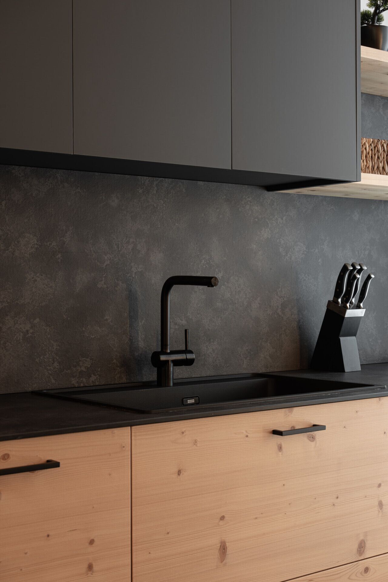 Una cocina moderna con un grifo negro, armarios de madera y un bloque de cuchillos.
