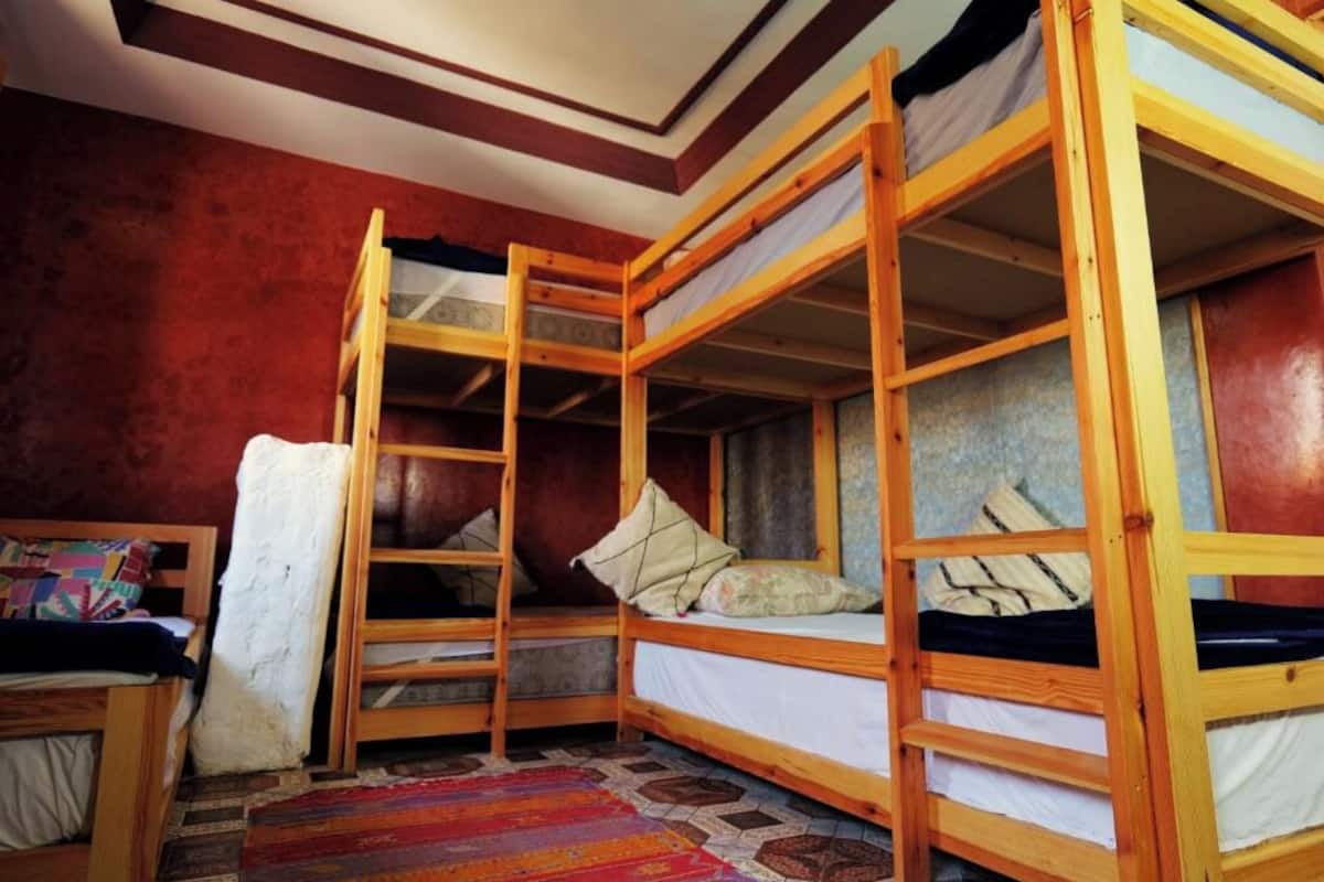 Una habitación con tres literas, un tapete colorido y un cabecero de madera.