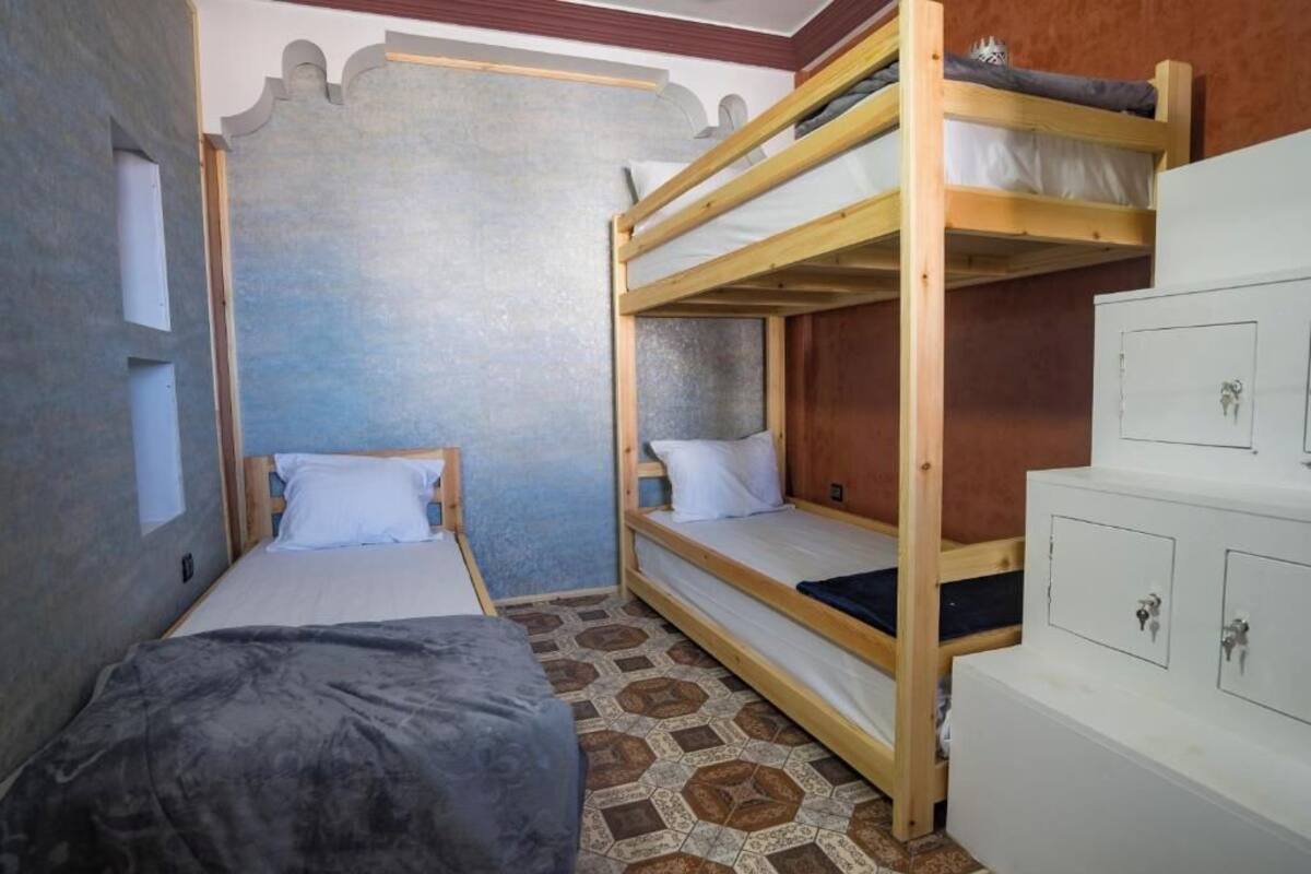 Un dormitorio con literas, una cama individual y un aparador con cajones.