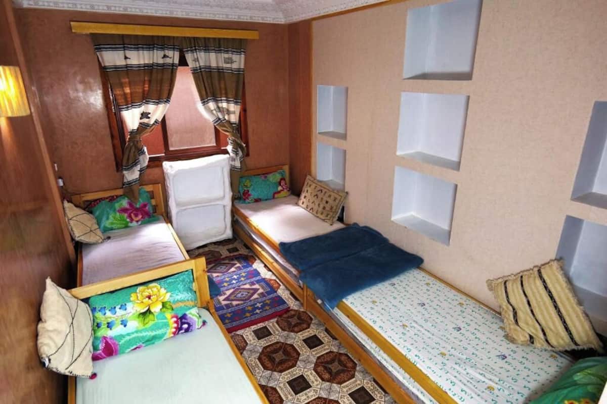 Una habitación compacta con dos camas, una mesita y una silla.