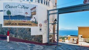 Un complexe résidentiel appelé « Ocean View », doté d’une façade en pierre, d’une fresque représentant une scène de plage et offrant une vue dégagée sur la mer.