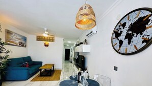 Un salon moderne avec un canapé bleu, une table basse en verre et un luminaire suspendu.
