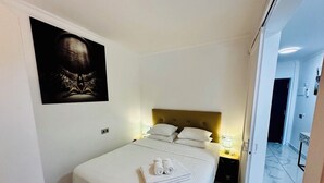 Une chambre d’hôtel avec un lit, une tête de lit, une table de chevet, une lampe et un tableau au mur.
