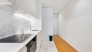 A modern kitchen with a marble countertop, stainless steel sink, and wooden flooring.