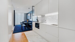 A modern kitchen with white cabinetry, a marble countertop, and a built-in oven.