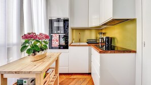 Una cocina moderna con armarios blancos, una encimera de madera y un horno empotrado.