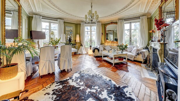 Una habitación lujosa con un espejo grande, muebles elegantes y un patrón de suelo en espiga.