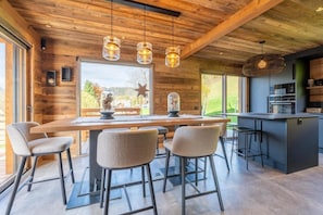 Una cocina moderna con una isla central, taburetes de bar e iluminación colgante.